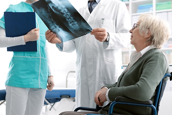 Dr. Grigory Goldberg reviewing a CT scan of a spine surgery patient showing spinal deformity during a pre-surgery consultation.
